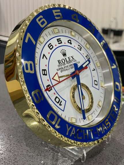 Luxurious stainless steel wall clock. Yacht master ll in yellow gold - blue bezel and white face.